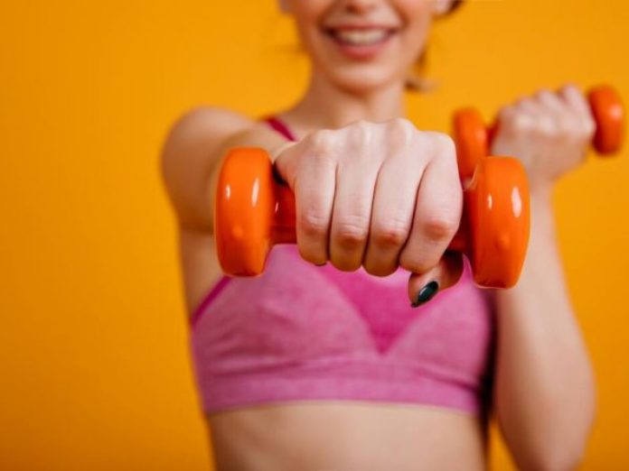 smiling girl posing with dumbbels athletic young woman training yellow background1 600 450 80 s c1